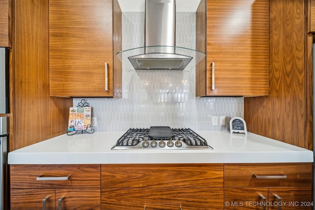 kitchen featuring wall chimney range hood, stainless steel gas cooktop, and tasteful backsplash