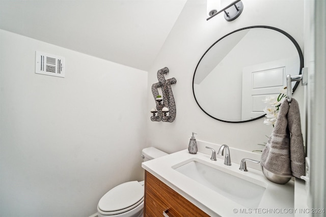 bathroom with vanity, toilet, and lofted ceiling