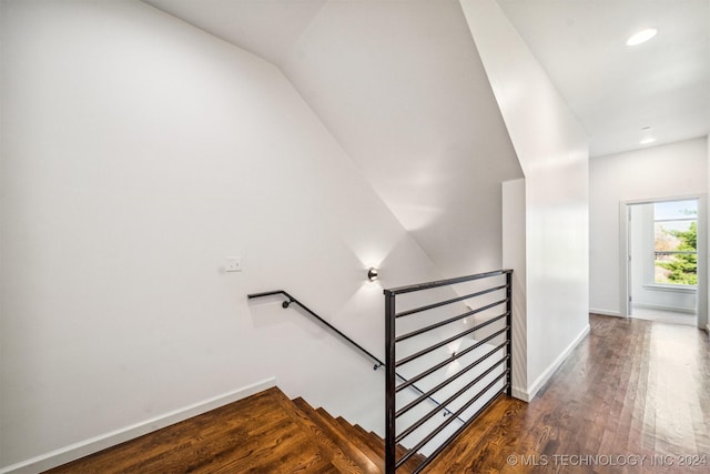 staircase with wood-type flooring and lofted ceiling