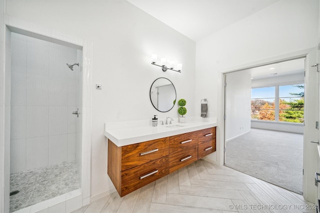 bathroom with tiled shower and vanity