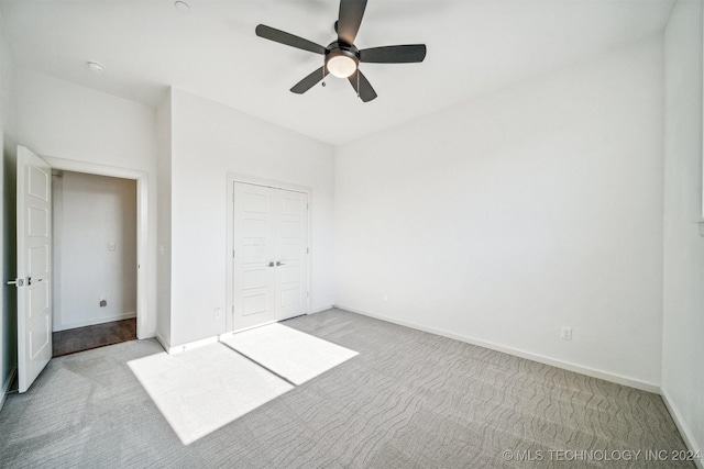 unfurnished bedroom featuring light carpet, a closet, and ceiling fan