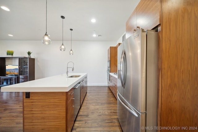 kitchen with dark hardwood / wood-style flooring, stainless steel appliances, sink, decorative light fixtures, and an island with sink