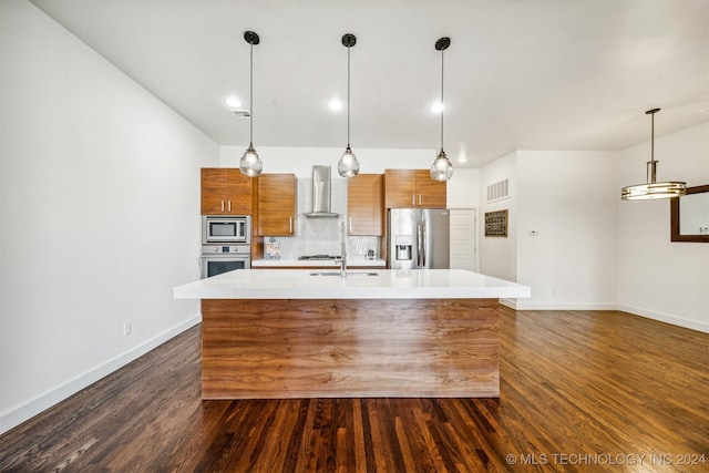 kitchen with appliances with stainless steel finishes, dark hardwood / wood-style floors, a kitchen island with sink, and wall chimney exhaust hood