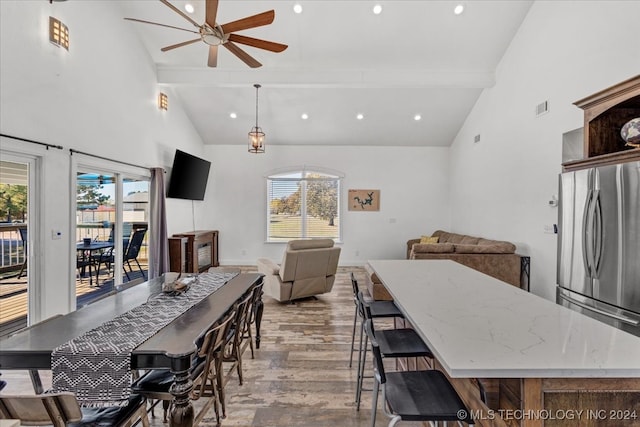 dining area with beam ceiling, light hardwood / wood-style floors, high vaulted ceiling, and ceiling fan