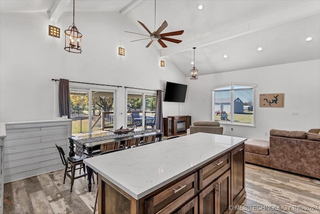 kitchen featuring beamed ceiling, ceiling fan with notable chandelier, light wood-type flooring, and hanging light fixtures