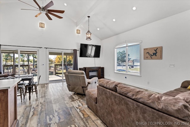 living room featuring beam ceiling, light wood-type flooring, high vaulted ceiling, and ceiling fan