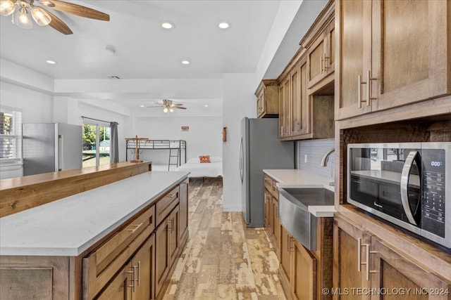 kitchen with ceiling fan, sink, tasteful backsplash, light hardwood / wood-style flooring, and appliances with stainless steel finishes