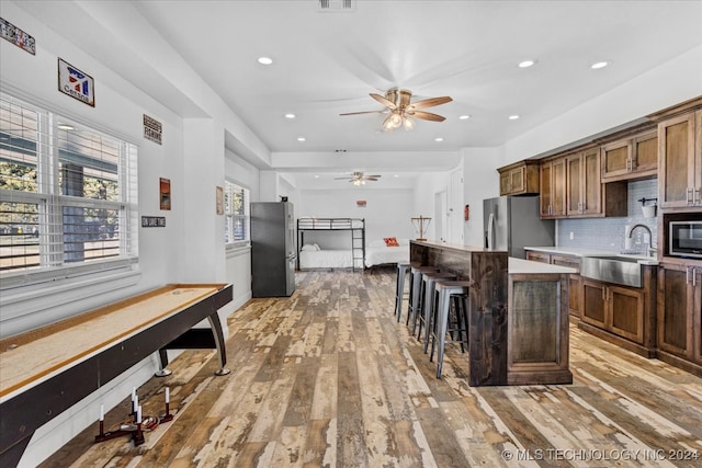 kitchen featuring sink, a center island, stainless steel appliances, light hardwood / wood-style flooring, and a breakfast bar area