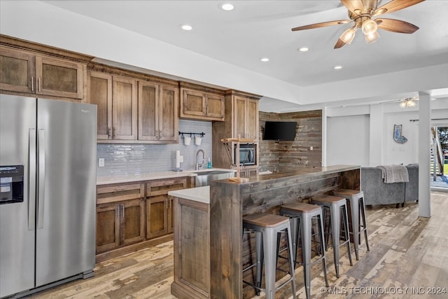 kitchen with decorative backsplash, sink, stainless steel appliances, and light wood-type flooring