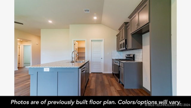 kitchen with appliances with stainless steel finishes, dark hardwood / wood-style flooring, backsplash, sink, and a center island with sink