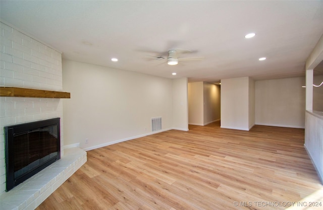 unfurnished living room featuring ceiling fan, light wood-type flooring, and a fireplace