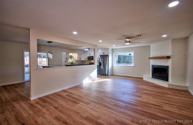 unfurnished living room featuring a fireplace, hardwood / wood-style floors, and ceiling fan