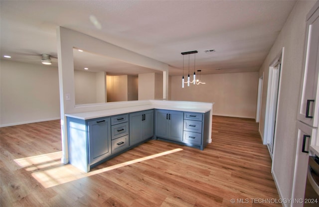 kitchen with kitchen peninsula, light hardwood / wood-style flooring, pendant lighting, and ceiling fan with notable chandelier