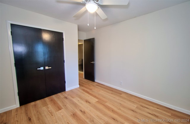 unfurnished bedroom with ceiling fan, light hardwood / wood-style floors, and a closet