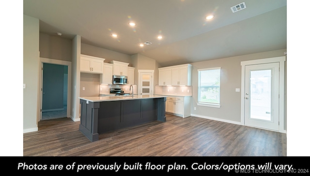 kitchen featuring stainless steel appliances, white cabinetry, lofted ceiling, and a center island with sink