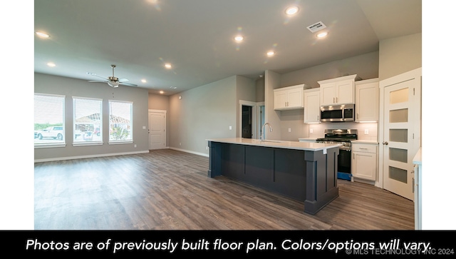 kitchen with white cabinets, appliances with stainless steel finishes, a kitchen island with sink, and sink