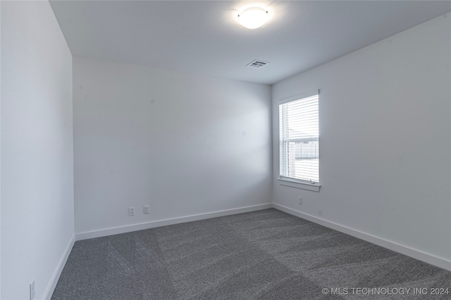 spare room featuring dark colored carpet