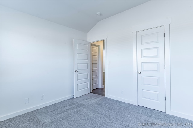 unfurnished bedroom with carpet flooring, a closet, and lofted ceiling