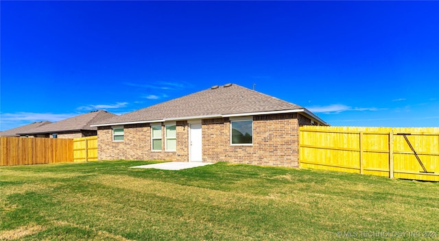 back of house with a lawn and a patio