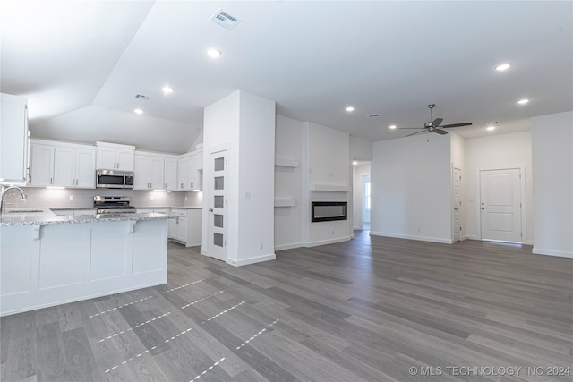 kitchen with light stone countertops, stainless steel appliances, vaulted ceiling, ceiling fan, and white cabinets