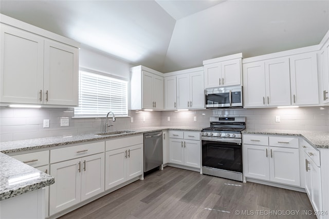 kitchen with white cabinetry, sink, appliances with stainless steel finishes, and vaulted ceiling