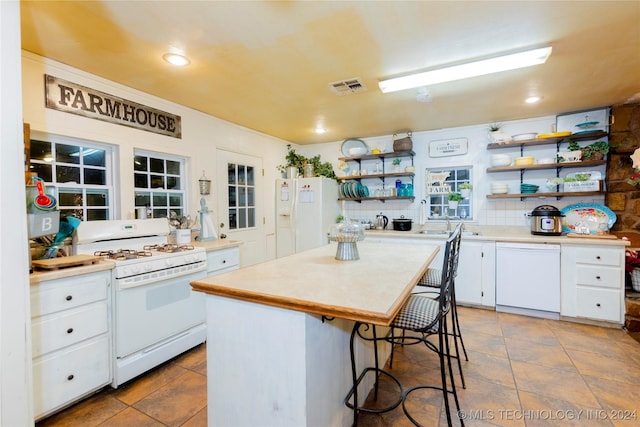 kitchen featuring white appliances, tasteful backsplash, white cabinetry, and a kitchen island