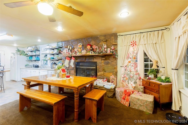 tiled dining room featuring a fireplace and ceiling fan