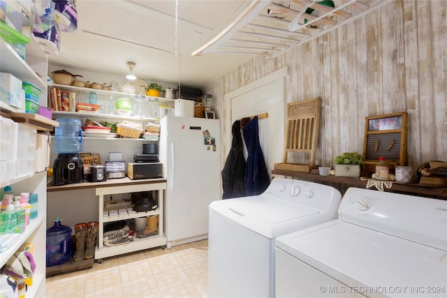 clothes washing area with washing machine and dryer and wooden walls