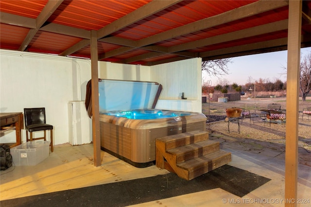 patio terrace at dusk featuring a hot tub