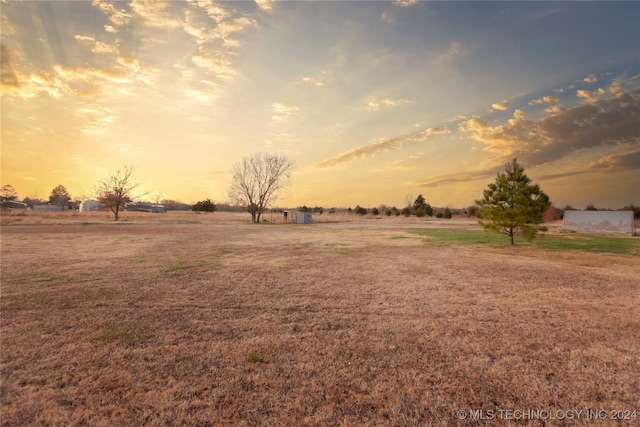 yard at dusk featuring a rural view