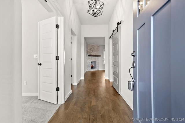 hall featuring dark hardwood / wood-style floors, a barn door, and a chandelier