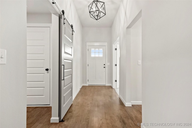 doorway to outside with a chandelier, a barn door, and hardwood / wood-style flooring