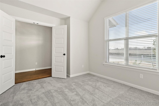 unfurnished bedroom with light colored carpet and lofted ceiling