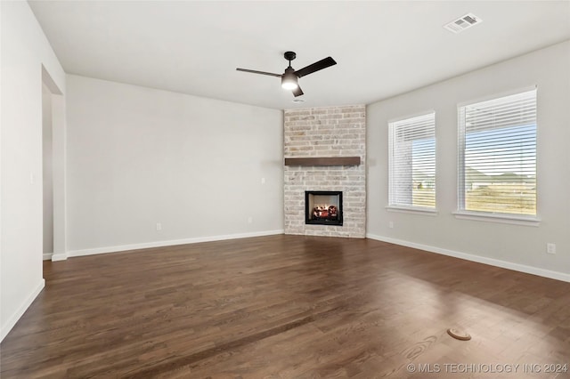 unfurnished living room featuring ceiling fan, dark wood-type flooring, and a brick fireplace