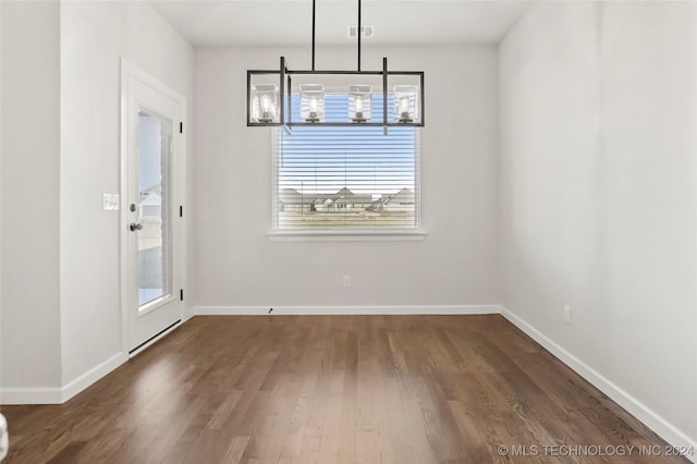 unfurnished dining area with dark hardwood / wood-style flooring and a chandelier