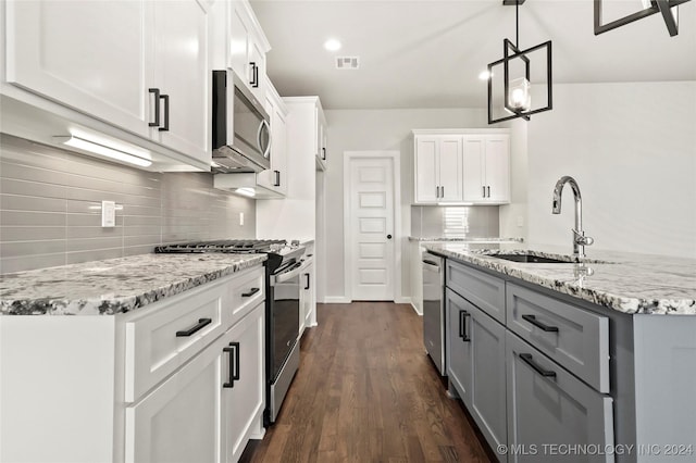 kitchen featuring appliances with stainless steel finishes, sink, pendant lighting, dark hardwood / wood-style floors, and white cabinetry