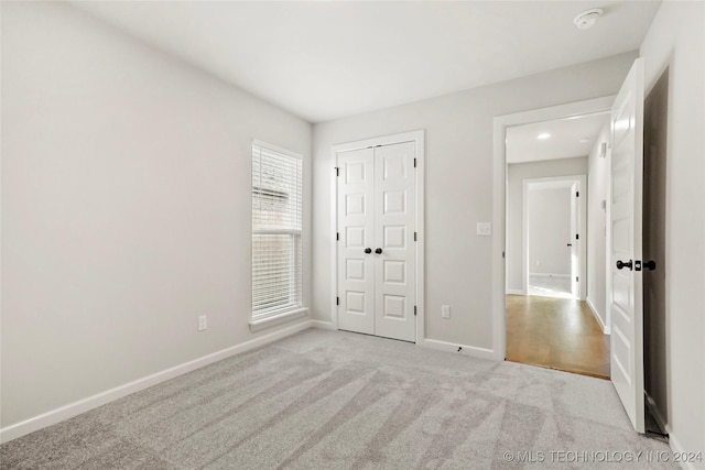 unfurnished bedroom featuring light colored carpet and a closet