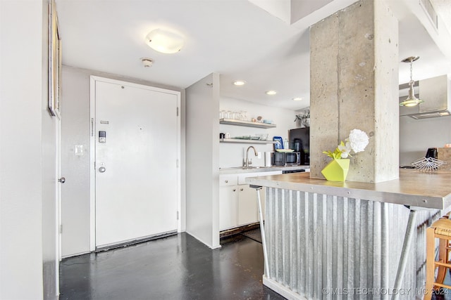 kitchen with white cabinets, decorative light fixtures, a kitchen bar, and sink