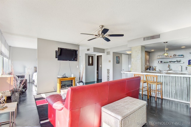 living room with ceiling fan, sink, and a textured ceiling