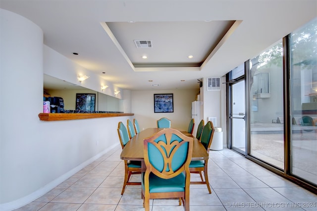 tiled dining area with a raised ceiling