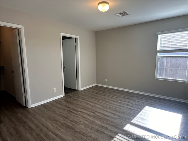 unfurnished bedroom with a walk in closet, dark hardwood / wood-style floors, and a closet