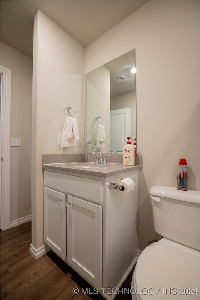 bathroom with wood-type flooring, vanity, and toilet