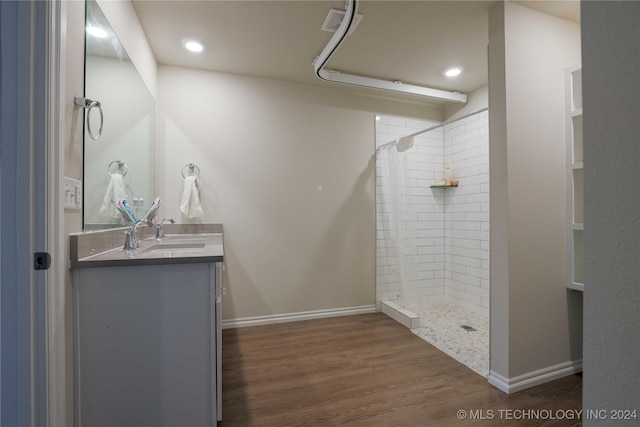 bathroom with a tile shower, vanity, and wood-type flooring