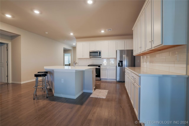 kitchen featuring white cabinetry, a kitchen breakfast bar, dark hardwood / wood-style floors, a center island with sink, and appliances with stainless steel finishes