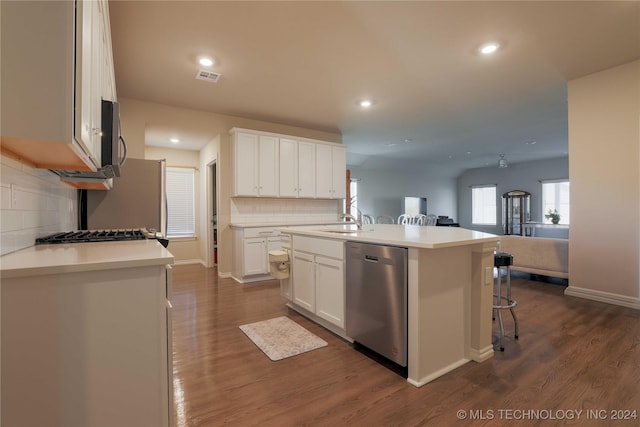 kitchen with white cabinetry, dark wood-type flooring, stainless steel dishwasher, an island with sink, and decorative backsplash