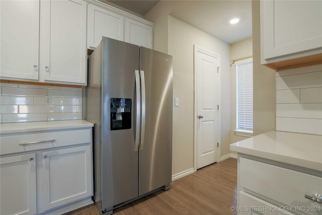 kitchen featuring white cabinets, light hardwood / wood-style floors, stainless steel fridge with ice dispenser, and tasteful backsplash