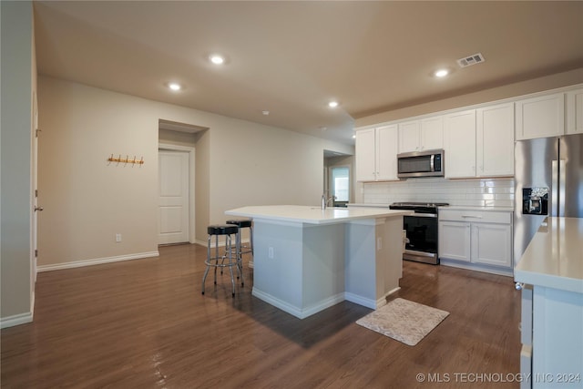 kitchen with appliances with stainless steel finishes, backsplash, dark hardwood / wood-style flooring, white cabinetry, and an island with sink