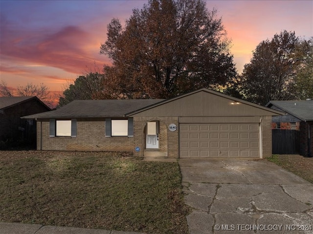 ranch-style home featuring a garage and a yard