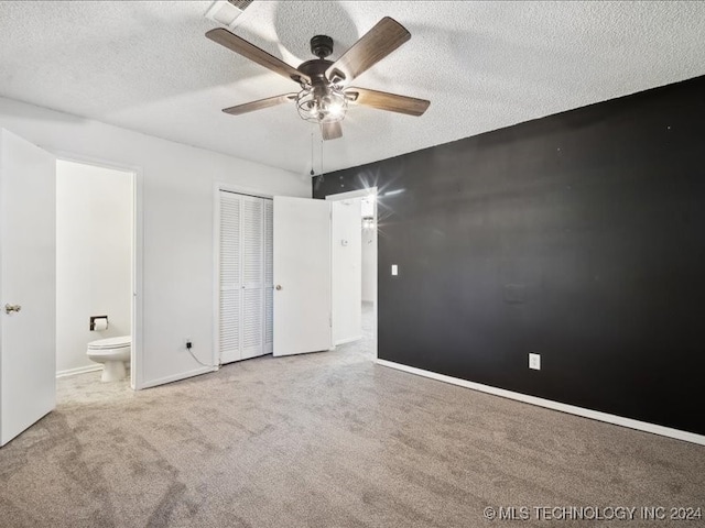 unfurnished bedroom with ceiling fan, ensuite bathroom, light colored carpet, a textured ceiling, and a closet