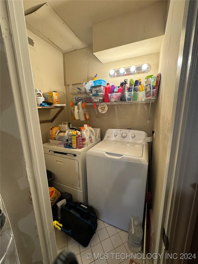 clothes washing area featuring light tile patterned floors and washing machine and clothes dryer